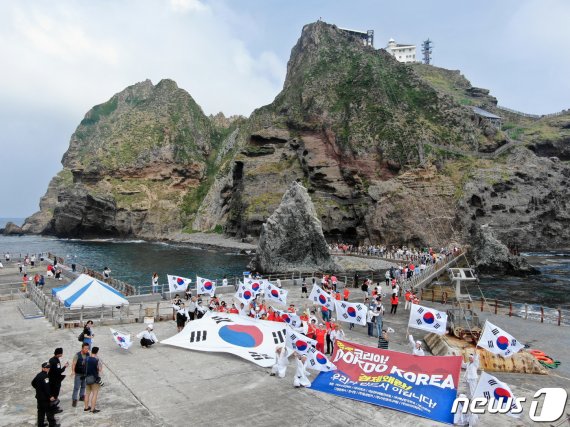 10일 경상북도 울릉군 독도를 찾은 멀티암벽 산악회(대장 이재석, 엄재선, 차금호, 박경모) 오윤숙을 비롯한 대원들이 관광객과 함께 대형 태극기를 펼치며 '한·일 경제위기&경제왜란, 하나되어 이겨냅시다' 퍼포먼스를 펼치고 있다. 2019.8.10/뉴스1 © News1 박세연 기자