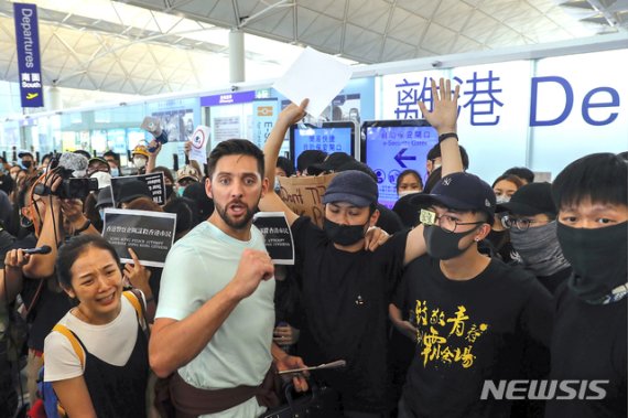 【홍콩=AP/뉴시스】 홍콩 국제공항에서 지난 13일 저녁 공항 당국이 항공사의 체크인 업무를 전면 중지시킨 후 출국장 점거 시위대는 수하물 카트로 출국 게이트로 가는 통로를 막아버렸다. 이에 어렵게 체크인을 끝내 비행기를 타려던 한 부부가 게이트를 바로 앞에 두고 길이 막혀버렸다. 남편은 화를 내고 시위대와 언쟁을 하고 부인은 안타까움에 울먹이고만 있다. 2019.08.13.
