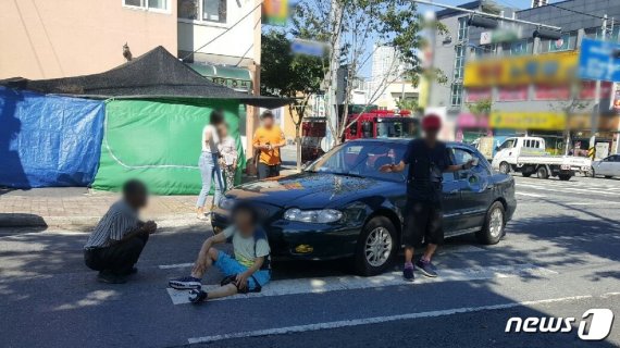 13일 오전 9시 20분께 한 남성이 몰던 승용차에 하반신이 깔렸다가 시민들의 구조로 위기에서 벗어난 할머니가 도로 한가운데에 앉아있다. (제공=대전지방경찰청)© 뉴스1