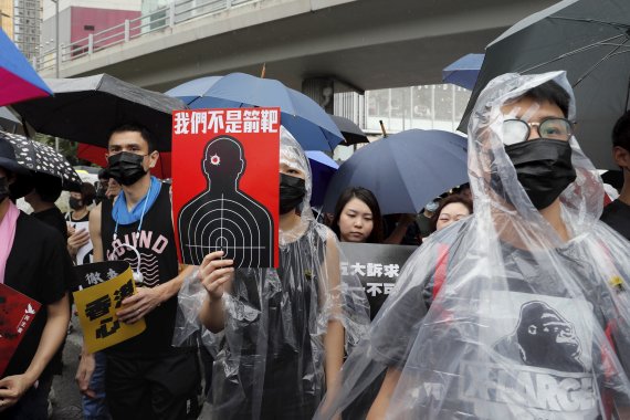 '범죄인 인도 법안' 반대 대규모 집회가 벌어진 18일 홍콩 도심에서 한 시위대가 '우리는 타깃이 아니다'라고 적힌 피켓을 들고 있다. 이들은 앞선 시위에서 경찰이 쏜 빈백건에 맞아 실명 위기에 처한 여성에 대한 연대를 보여주기 위해 안대를 쓰고 있다. AP뉴시스