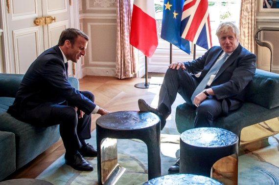 보리스 존슨 영국 총리(오른쪽)가 22일(현지시간) 프랑스 파리 엘리제궁에서 열린 에마뉘엘 마크롱 프랑스 대통령과 정상회담에서 발을 탁자 위에 올려놓고 있다.로이터뉴스1