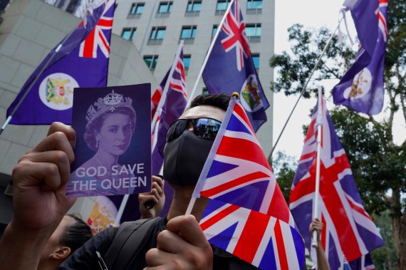 英국기 흔드는 반중 시위대, 여왕에 SOS/홍콩 시위가 친중과 반중 세력의 충돌 구도로 전환되고 있는 가운데 반중을 외치는 시위대가 15일 홍콩 주재 영국총영사관 앞에서 영국 국기와 영국 여왕 사진이 들어간 피켓을 흔들고 있다. 이들은 중국이 과거 홍콩을 식민지배했던 영국과 지난 1984년 서명한 홍콩반환협정 내용인 홍콩의 자유와 자치권에 대한 약속을 이행할 것을 촉구했다. AP뉴시스