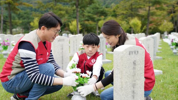 롯데건설 임직원과 가족이 지난 21일 서울 동작동 국립서울현충원에서 묘역단장을 하고 있다.