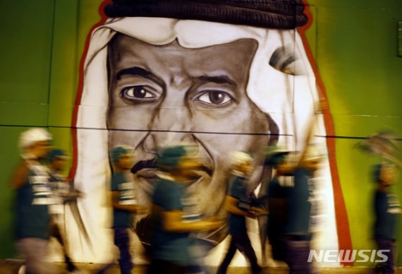 【리야드=AP/뉴시스】사우디아라비아 국립기념일인 23일(현지시간) 수도 리야드 거리에서 시민들이 살만 빈 압둘아지즈 사우디 국왕의 벽화 앞을 지나고 있다. 2019.09.24.