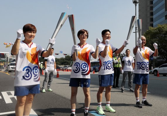 29일 오후 제100회 전국체육대회와 장애인전국체전 성화봉송 주자인 서울 아시안게임 3관왕 임춘애씨(왼쪽 두번째부터)와 사격 진종오 선수가 성화봉송을 마치고 다음주자인 여자핸드볼 은메달리스트 임오경(왼쪽), 주원홍 아시아테니스연맹 부회장에서 성화를 옮기고 있다. 사진=서동일 기자