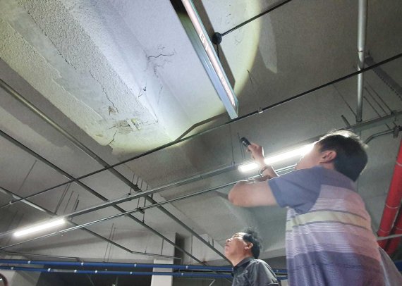 부산 금곡동 동원역 삼정그린코아 아파트의 한 입주민이 지하 주차장에서 발생한 균열을 비추고 있다.