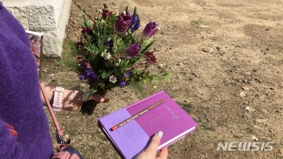 김민정 시인이 허수경 시인 1주기 추모제에 참석, 유고집 '가기 전에 쓰는 글들'과 꽃, 연필 한 자루를 손에 들고 있다. ⓒ출판사 난다
