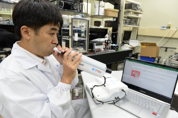 한국전자통신연구원 박형주 선임연구원이 '전자 코' 시스템에 넣을 날숨을 채취하고 있다. 한국전자통신연구원 제공