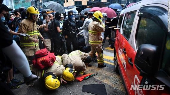 【서울=뉴시스】복면금지법 시행에 반대하는 시위가 계속되는 홍콩에서 6일 택시 1대가 시위대를 향해 돌진, 2명이 차 밑에 깔리고 택시 운전자가 시위대에 구타당하는 사건이 발생했다. 사고 후 구조대원들이 택시 아래 깔린 부상자들을 구조하기 위해 노력하고 있다. <사진 출처 : CNN> 2019.10.7
