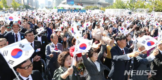 제573돌 한글날 경축식이 열린 9일 오전 서울 광화문광장에서 참석자들이 태극기를 들고 만세삼창을 하고 있다.