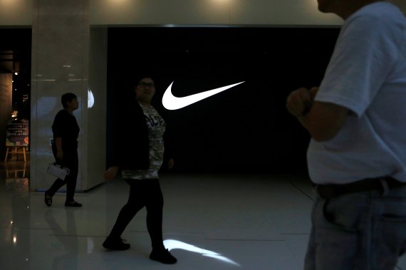 People walk past a Nike logo outside its store at a shopping mall in Beijing, China October 10, 2019. REUTERS/Tingshu Wang /REUTERS/뉴스1 /사진=