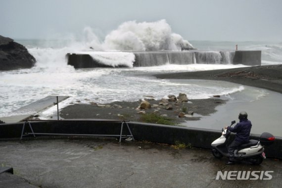 12일 일본 미에현 구마노 해변에 제19호 태풍 '하기비스'의 영향으로 거센 파도가 방파제를 덮치는 모습을 한 남성이 스쿠터에 앉아 바라보고 있다. /사진=뉴시스