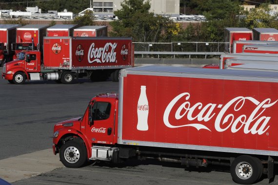 In this Monday, Oct. 14, 2019 photo a truck with the Coca-Cola logo, behind left, maneuvers in a parking lot at a bottling plant in Needham, Mass. The Coca-Cola Co. reports financial results Friday, Oct. 18. (AP Photo/Steven Senne) /뉴시스/AP /사진=