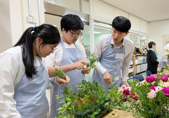 지난 4월 말 서울 신교동 국립서울농학교에서 진행된 '블루밍데이' 봉사활동에서 한화투자증권 직원과 학생이 함께 꽃으로 작품을 만들고 있다(오른쪽 사진). 한화투자증권 제공