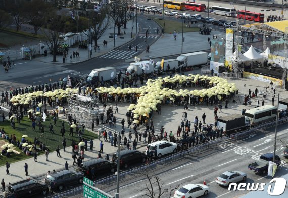 14일 오후 4시 16분에 서울 광화문광장에서 열린 세월호 참사 5주기 ‘잊지 않을게’ 대학생 대회에서 참가자들이 노란 우산으로 세월호 리본을 만드는 퍼포먼스를 하고 있다. 2019.4.13/뉴스1 © News1 신웅수 기자