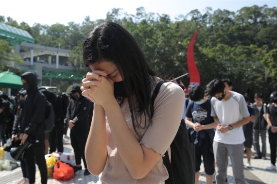 Protesters pause for a moment of silence after disrupting a graduation ceremony at the University of Science and Technology and turning the stage into a memorial venue for Chow Tsz-Lok in Hong Kong on Friday, Nov. 8, 2019. Chow, a student from the University who fell off a parking garage after polic