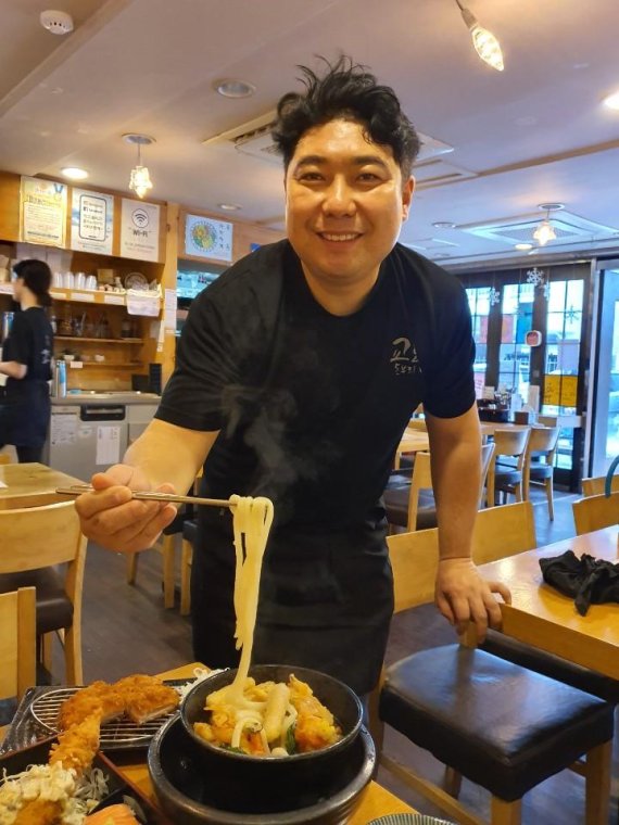 박호용 대표가 감칠맛을 더하는 얼큰한 국물을 자랑하는 인기 메뉴인 우동 면발을 들어보이고 있다.