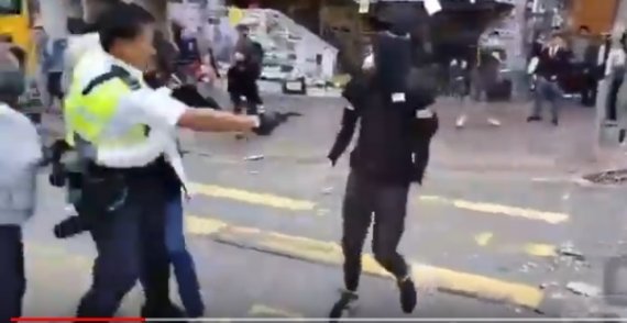 홍콩 사이완호 지역에서 11일 오전 경찰 한 명이 검은색 옷을 입고 얼굴을 가린채 다가오는 시위 참가자를 향해 총을 쏘고 있다. 이 사람은 실탄에 맞아 부상을 입은 것으로 전해지고 있다. [사진=유튜브/뉴시스]