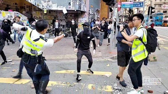 11일 홍콩섬 북동부 사이완호 지역에서 반정부 시위자와 실랑이를 벌이는 경찰(왼쪽)이 자신에게 다가오는 검은 옷의 청년을 향해 총을 겨누고 있다. 청년은 이날 실탄 1발을 맞아 후송됐으나 위독한 상태라고 알려졌다.로이터뉴스1