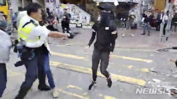 【홍콩=AP/뉴시스】11일(현지시간) 온라인에 유포된 동영상 속에서 한 홍콩 경찰관이 시위 현장에서 다가오는 시위자를 향해 총을 겨누고 있다. 현지 언론은 이날 오전 홍콩 사이완호 지역에서 시위 희생자 차우츠록을 추모하는 시위가 열린 가운데 시위대 한 사람이 경찰이 발사한 실탄에 맞아 쓰러져 병원으로 이송돼 치료를 받고 있다고 전했다. 2019.11.11.