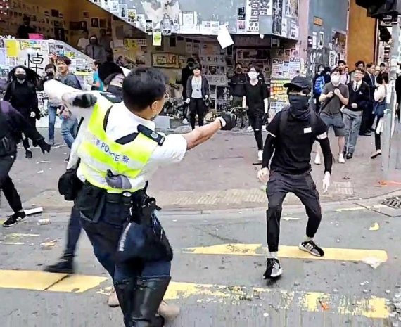 11일 홍콩섬 북동부 사이완호 지역에서 반정부 시위자와 실랑이를 벌이는 경찰(왼쪽)이 자신에게 다가오는 검은 옷의 청년을 향해 총을 겨누고 있다. 로이터 뉴스1