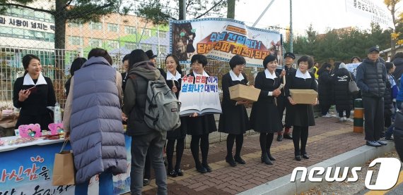 천안 월봉고 앞에서 수능 1세대 엄마들이 교복을 입고 수험생들을 응원하고 있다. © 뉴스1
