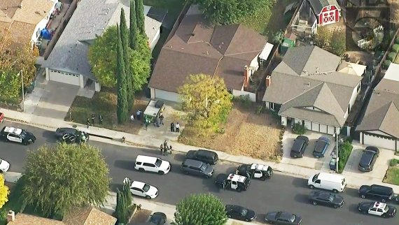 This photo from video provided by KTLA-TV shows police vehicles filling the street in front of the home of the alleged shooter, with the brown roof at center, after a shooting at Saugus High School in Santa Clarita, Calif., early Thursday, Nov. 14, 2019. (KTLA-TV via AP) /뉴시스/AP /사진=