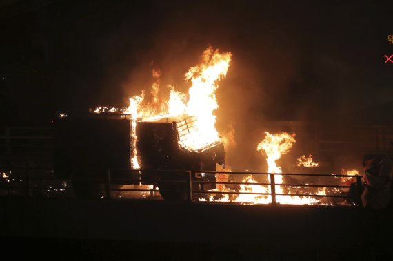 An armored police vehicle catches fire after being hit by molotov cocktails thrown by protestors on a bridge over a highway leading to the Cross Harbour Tunnel in Hong Kong, Sunday, Nov. 17, 2019. A Hong Kong police officer was hit in the leg by an arrow Sunday as authorities used tear gas and water