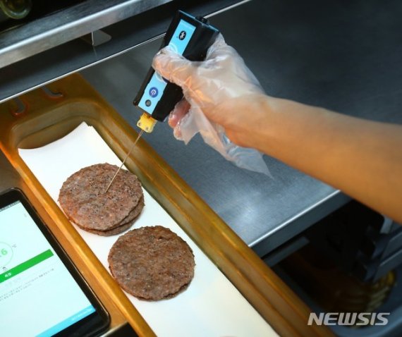 [서울=뉴시스]맥도날드 매장 주방에서 갓 구워진 소고기 패티 온도를 디지털 온도계와 태블릿 PC로 측정하는 모습 (사진=한국맥도날드 제공)