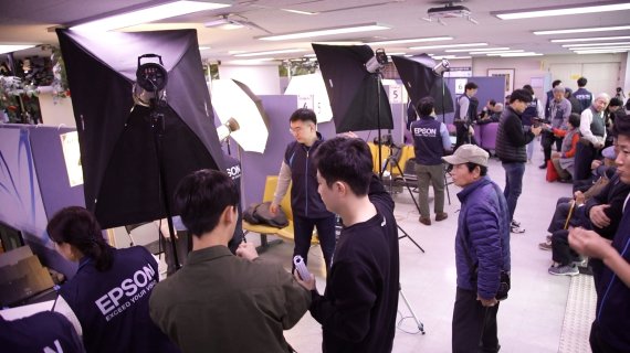 한국엡손 직원들이 서울노인복지센터에서 사진을 찍고 출력해주는 봉사활동을 하고 있다.