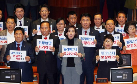 한국당은 더불어민주당에 맞서 본회의장에서 개의를 촉구하는 문구를 들고 구호를 외쳤다. 뉴시스