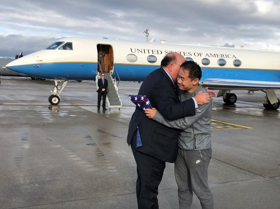This photo provided by U.S. Embassy Switzerland, Edward McMullen greets Xiyue Wang after landing in Zurich, Switzerland on Saturday, Dec. 7, 2019. In a trade conducted in Zurich, Iranian officials handed over Chinese-American graduate student Xiyue Wang, detained in Tehran since 2016, for scientist 