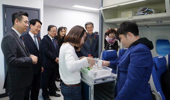 한태근 에어부산 사장(왼쪽 두번째)과 김석준 부산시교육감(왼쪽 세번째)을 비롯한 관계자들이 에어부산 직업체험관에서 실습하고 있는 발달장애 학생을 보고 있다. /사진=에어부산