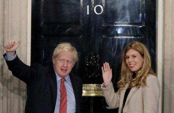 Britain's Prime Minister Boris Johnson and his partner Carrie Symonds wave from the steps of number 10 Downing Street in London, Friday, Dec. 13, 2019. Prime Minister Boris Johnson's Conservative Party has won a solid majority of seats in Britain's Parliament ??a decisive outcome to a Brexit-dominat