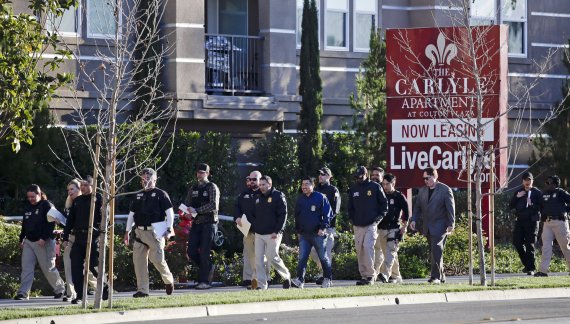 FILE - In this March 3, 2015 file photo, federal agents enter an upscale apartment complex where authorities say a birth tourism business charged pregnant women $50,000 for lodging, food and transportation, in Irvine, Calif. A Chinese woman was sentenced to 10 months in prison Monday, Dec. 16, 2019,