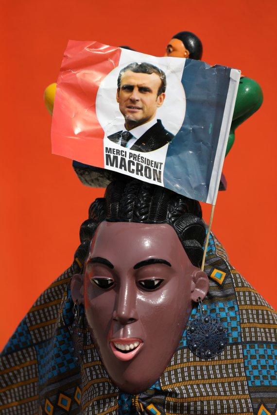 지난 21일(현지시간) 코트디부아르 아비장에서 촬영된 전통 가면에 에마뉘엘 마크롱 프랑스 대통령의 사진이 들어간 프랑스 국기가 꼿혀 있다.로이터뉴스1