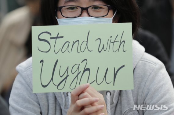 [홍콩=AP/뉴시스] 22일 홍콩 도심에서 한 시위자가 "신장위구르족을 지지한다'는 문구가 적힌 종이를 들고 시위를 벌이고 있다. 이날 홍콩에서 중국 당국의 신장자치구위구르족 인권 침해를 반대하며 위구르족과의 연대를 주장하는 시위가 최초로 열렸다. 2019.12.22