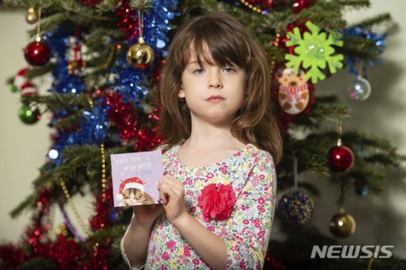 [런던=AP/뉴시스]영국의 6세 소녀 플로렌스 위디콤이 구매한 크리스마스 카드에서 중국 내 외국인 재소자들이 강제 노역을 폭로하는 글귀가 써있었다고 22일(현지시간) BBC, 텔레그래프 등이 보도했다. 카드를 판매한 유통업체 테스코는 해당 카드들을 전면 판매 중지한다고 밝혔다. 사진은 문제가 된 카드를 든 위디콤의 모습. 2019.12.23. /사진=뉴시스