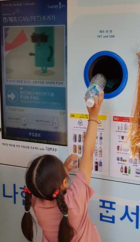 제주를 방문한 한 어린이 관광객이 '페트병 자동수거 보상기'에 페트병을 투입하고 있다. 제주특별자치도개발공사 제공