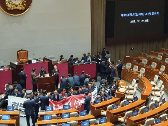 자유한국당 의원들이 27일 오후 서울 여의도 국회에서 열린 제373회 국회 (임시회) 본회의에 처리를 앞둔 공직선거법 일부개정법률안을 저지하기 위해 연단을 둘러싸 막고 있다.