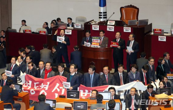 자유한국당 의원들이 공직선거법 개정안 통과를 막기 위해 27일 오후 서울 여의도 국회 본회의장 의장석을 포위하고 있다. 뉴시스