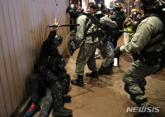[홍콩=AP/뉴시스] 25일 홍콩 경찰이 곤봉을 쳐들고 한 청년을 땅에 쓰려트려 꼼짝못하게 억누르고 있다. 2019. 12. 27.