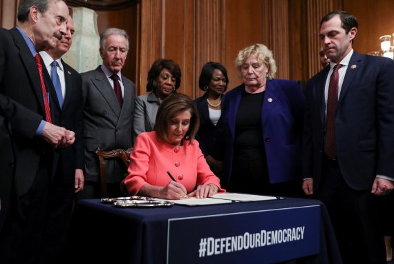 U.S. House Speaker Nancy Pelosi (D-CA) is surrounded by the House impeachment managers and committee chairs as she signs the two articles of impeachment of U.S. President Donald Trump before sending them over to the U.S. Senate during an engrossment ceremony at the U.S. Capitol in Washington, U.S., 