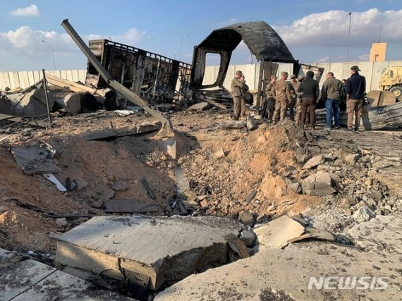 [아인알아사드=AP/뉴시스]미 군인들과 기자들이 13일(현지시간) 이라크 아인알아사드 공군기지에 남은 미사일 흔적 옆에 서 있다. 이 기지는 지난 8일 이란의 '가셈 솔레이마니 폭살' 보복공습을 받았다. 2020.01.14.