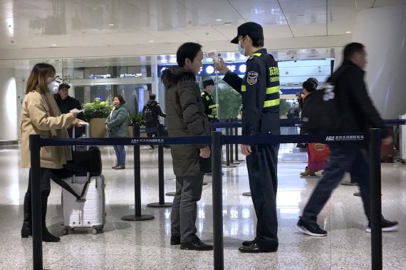 중국 후베이성 우한의 톈허 국제공항에서 21일 공항 관계자들이 온도계를 들고 여행객들을 검사하고 있다. AP뉴시스