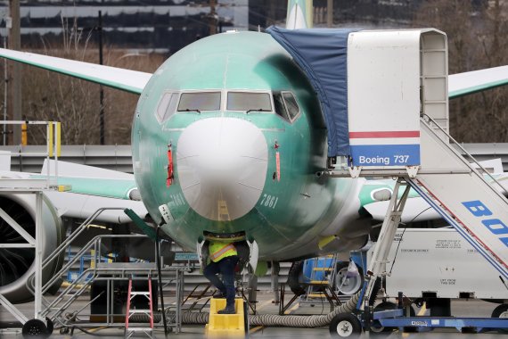 FILE - In this Dec. 16, 2019, file photo a worker looks up underneath a Boeing 737 MAX jet in Renton, Wash. Boeing doesn't expect federal regulators to approve its changes to the grounded 737 Max until this summer, according to two people familiar with the matter. (AP Photo/Elaine Thompson, File) /뉴