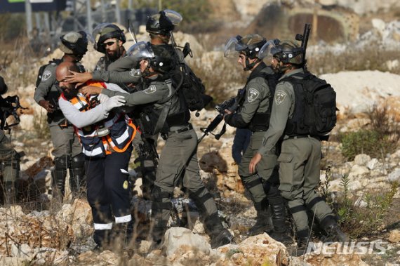 【서안지구=AP/뉴시스】16일(현지시간) 요르단강 서안지구 라말라 인근 베이엘 검문소에서 이스라엘의 가자지구 공습에 항의하는 팔레스타인 시위대 남성이 이스라엘군에 의해 다쳐 그에게 접근하려는 한 팔레스타인 구급대원이 이스라엘 보안군에 제지당하고 있다. 부상 시위자는 이스라엘 보안군에 체포되지 않고 팔레스타인 구급대에 넘겨졌다. 2019.11.17.