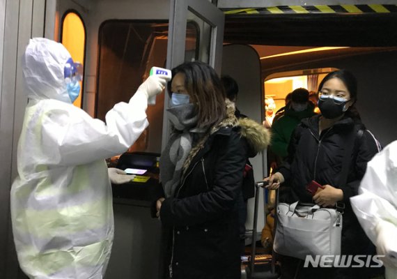 보호복을 입은 보건 관계자들이 지난 22일 중국 베이징 공항에서 우한시에서 도착한 승객들의 체온을 체크하고 있다. 중국은 신종 코로나바이러스로 발생하는 우한 폐렴의 확산을 막기 위해 지난 23일부터 모든 항공기와 열차들의 우한 출발을 막기 시작했다.