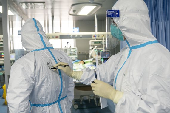 In this photo released by China's Xinhua News Agency, a medical worker writes their colleague's name on a protective suit to aid in identification as they work at Zhongnan Hospital of Wuhan University in Wuhan in central China's Hubei Province, Firday, Jan. 24, 2020. China announced Friday that it i