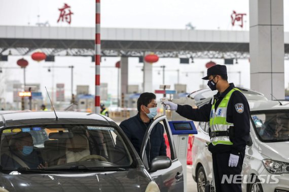 지난 23일(현지시간) 신종 코로나바이러스가 발발한 중국 후베이성 우한의 고속도로 톨게이트에서 경찰이 한 운전자의 체온을 검사하고 있다. 뉴시스 제공